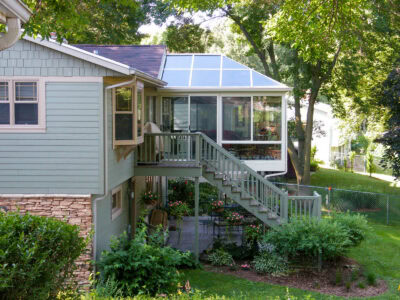 A bright, modern four-season sunroom in Southern Wisconsin featuring large energy-efficient glass windows, a cozy seating area, and top views of a beautifully landscaped backyard. This sunroom is made by Living Space, one of the top sunroom manufacturers in the country. 